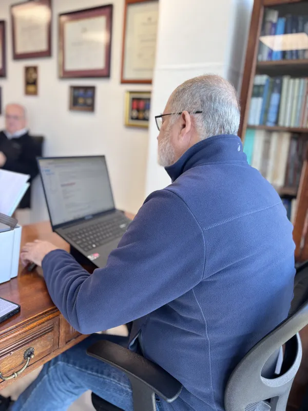 Abogado senior de CLM revisando información en su notebook junto a la biblioteca del estudio